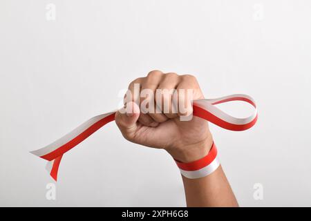 Die Hände werden mit roten und weißen Bändern als Symbol der indonesischen Flagge geballt, isoliert auf weißem Hintergrund. Indonesian Independence Day Concept, August Stockfoto