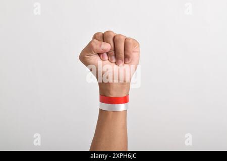 Die Hände werden mit roten und weißen Bändern als Symbol der indonesischen Flagge geballt, isoliert auf weißem Hintergrund. Indonesian Independence Day Concept, August Stockfoto