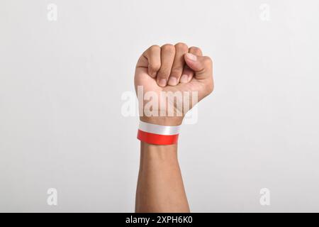 Die Hände werden mit roten und weißen Bändern als Symbol der indonesischen Flagge geballt, isoliert auf weißem Hintergrund. Indonesian Independence Day Concept, August Stockfoto