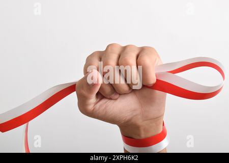 Die Hände werden mit roten und weißen Bändern als Symbol der indonesischen Flagge geballt, isoliert auf weißem Hintergrund. Indonesian Independence Day Concept, August Stockfoto