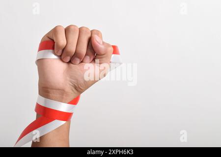 Die Hände werden mit roten und weißen Bändern als Symbol der indonesischen Flagge geballt, isoliert auf weißem Hintergrund. Indonesian Independence Day Concept, August Stockfoto