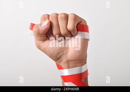 Die Hände werden mit roten und weißen Bändern als Symbol der indonesischen Flagge geballt, isoliert auf weißem Hintergrund. Indonesian Independence Day Concept, August Stockfoto