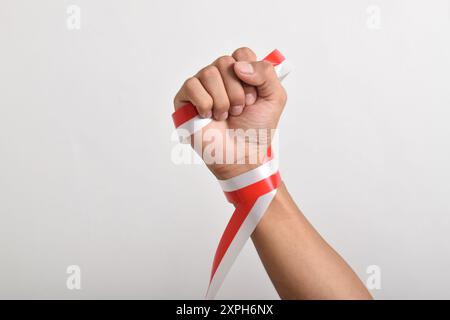 Die Hände werden mit roten und weißen Bändern als Symbol der indonesischen Flagge geballt, isoliert auf weißem Hintergrund. Indonesian Independence Day Concept, August Stockfoto