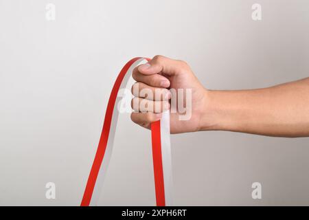 Die Hände werden mit roten und weißen Bändern als Symbol der indonesischen Flagge geballt, isoliert auf weißem Hintergrund. Indonesian Independence Day Concept, August Stockfoto