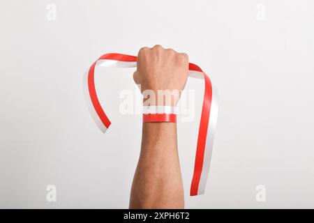 Die Hände werden mit roten und weißen Bändern als Symbol der indonesischen Flagge geballt, isoliert auf weißem Hintergrund. Indonesian Independence Day Concept, August Stockfoto