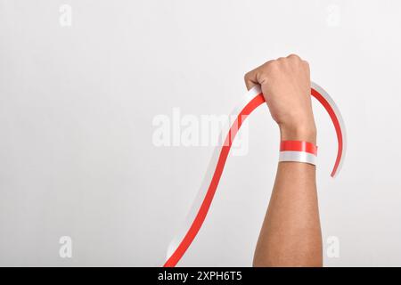 Die Hände werden mit roten und weißen Bändern als Symbol der indonesischen Flagge geballt, isoliert auf weißem Hintergrund. Indonesian Independence Day Concept, August Stockfoto