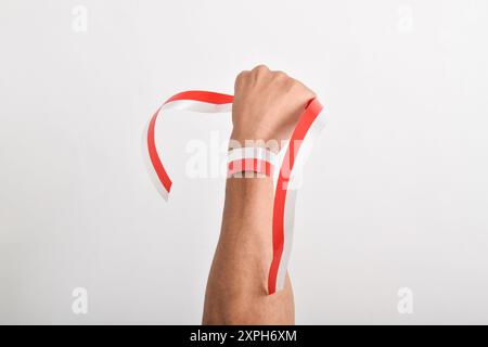 Die Hände werden mit roten und weißen Bändern als Symbol der indonesischen Flagge geballt, isoliert auf weißem Hintergrund. Indonesian Independence Day Concept, August Stockfoto