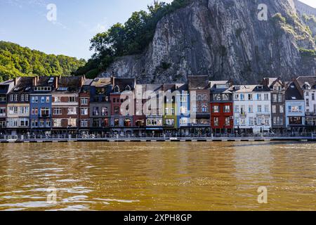 Stadtbild und Fluss Maas in Dinant, farbenfrohe Gebäude vor felsiger Bergmauer, touristische Restauranterrassen an der Promenade, sonniges Sum Stockfoto