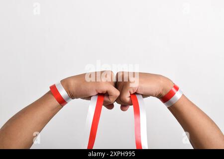 Geballt mit rotem und weißem Band als Symbol der indonesischen Flagge. Indonesian Independence Day Concept, 17. August. Vertrauen, Freundschaft, Teamwork Stockfoto