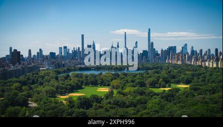 Lufthubschrauber-Aufnahmen über dem Central Park mit Natur, Bäumen, Picknickern und Ausruhen auf einem Feld rund um die Wolkenkratzer von Manhattan. Wunderschöner Sonniger Tag. Slow-Motion-Aufnahmen Stockfoto