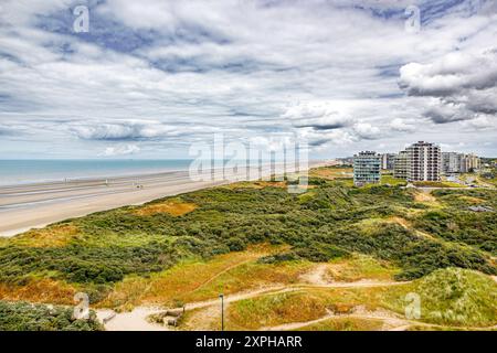 Panorama-Landschaft mit Dünen, Strand, Nordsee und Hochhäusern vor stürmischem Himmel bedeckt mit Wolken im Touristenzentrum de Panne, Horizont hinein Stockfoto