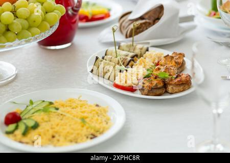 Hochzeitsbankett im Restaurant, überdachter runder Tisch für Gäste, weiße Teller mit Auberginen-Brötchen, Tomaten mit Käse und gebackenen Pilzen. Stockfoto