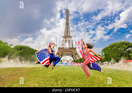 Patriotische Amerikanerin springt und jubelt für das Team USA und die Olympischen Spiele 2024 in Paris vor dem Eiffelturm, Paris, Frankreich, Europa Stockfoto