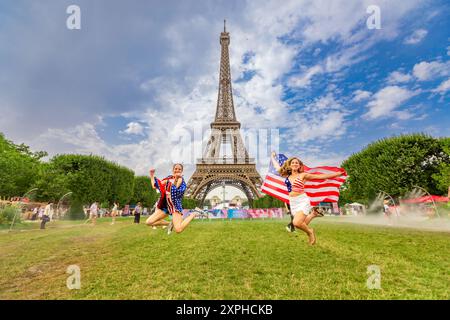 Patriotische Amerikanerin springt und jubelt für das Team USA und die Olympischen Spiele 2024 in Paris vor dem Eiffelturm, Paris, Frankreich, Europa Stockfoto