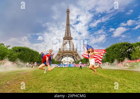 Patriotische Amerikanerin springt und jubelt für das Team USA und die Olympischen Spiele 2024 in Paris vor dem Eiffelturm, Paris, Frankreich, Europa Stockfoto