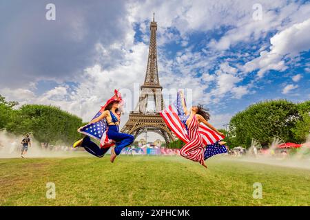 Patriotische Amerikanerin springt und jubelt für das Team USA und die Olympischen Spiele 2024 in Paris vor dem Eiffelturm, Paris, Frankreich, Europa Stockfoto