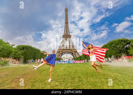 Patriotische Amerikanerin springt und jubelt für das Team USA und die Olympischen Spiele 2024 in Paris vor dem Eiffelturm, Paris, Frankreich, Europa Stockfoto