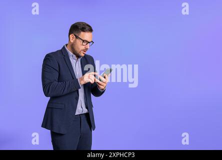 Ernstzunehmender besorgter männlicher Profi in eleganter Formalwear, der E-Mails über das Smartphone liest. Gestresster junger Geschäftsmann, der online schreibt, wh Stockfoto
