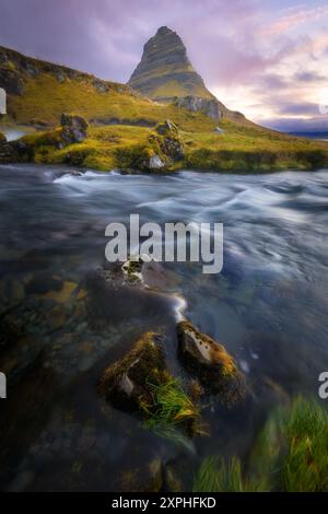 Majestätischer Berg Kirkjufell in Island bei Sonnenaufgang, langer Fluss im Vordergrund, vertikale Ausrichtung Stockfoto
