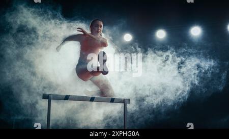 Läuferin springt über die Hürde bei dramatischem Rauch und hellen Lichtern, intensivem Fokus, Agilität und Stärke beim High-Energy Track and Field Event. Stockfoto