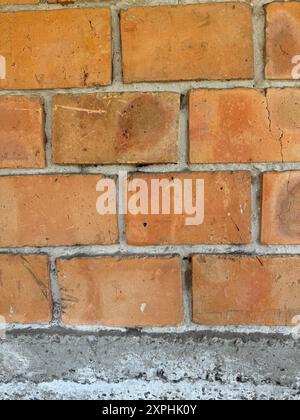 Rote Ziegelwand. Fragment eines Betonfundaments. Stockfoto