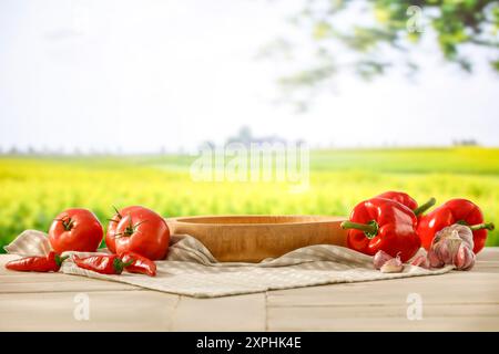 Tomaten und rote Paprika auf Holztisch mit sonnigem blauem Himmel und Frühling oder Sommer Garten Feld Hintergrund. Bild für die Anzeige von Montageobjekten. Stockfoto