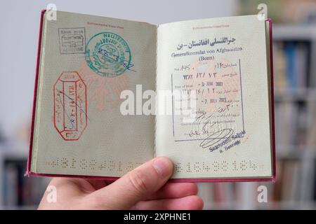 Hand hŠlt einen deutschen Reisepass mit Visa Stempeln von Afghanistan *** Hand mit deutschem Reisepass mit Visumstempel Stockfoto