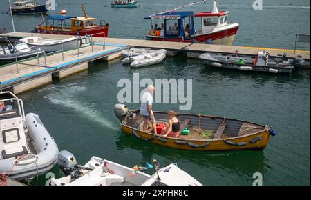 Ein kleines Holzboot, das von einem Außenbordmotor angetrieben wird, mit einem Mann und einer Frau, die an der Dittisham-Fähre in Dartmouth, Devon, Großbritannien, vorbeifahren Stockfoto