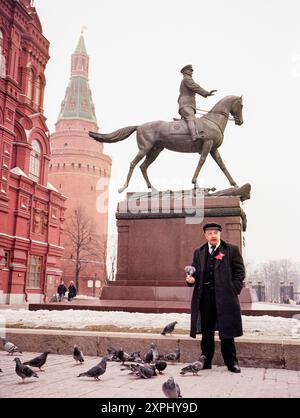 Ein Lenin-Imitator ernährt Tauben zu Füßen einer Zarenstatue auf dem Manezhnaja-Platz in Moskau. Das Bild wurde im April 2006 aufgenommen und zeigt historische Architektur und kulturelle Momente in Russland. Stockfoto