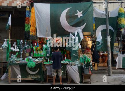 Pakistanische Flaggen, Buntstricke, bedruckte Hemden und andere Gegenstände werden im Zusammenhang mit dem bevorstehenden Unabhängigkeitstag Pakistans am Straßenstand in Gujranwala am Dienstag, den 6. August 2024 verkauft. Stockfoto