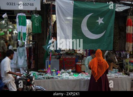 Pakistanische Flaggen, Buntstricke, bedruckte Hemden und andere Gegenstände werden im Zusammenhang mit dem bevorstehenden Unabhängigkeitstag Pakistans am Straßenstand in Gujranwala am Dienstag, den 6. August 2024 verkauft. Stockfoto