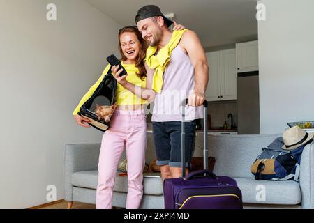 Mit Hund und Trailtaschen, die auf das Handy schauen und lächeln. Stockfoto