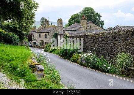 Grassington Yorkshire Großbritannien - 27. Juli 2024. Charmante ländliche Dorfstraße gesäumt von Steinhäusern und üppigem Grün an einem ruhigen Sommertag. Stockfoto