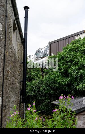 Grassington Yorkshire Großbritannien - 27. Juli 2024. Industriegebäude inmitten üppiger Grünanlagen mit einem hohen Kamin vor einem bewölkten Himmel. Stockfoto