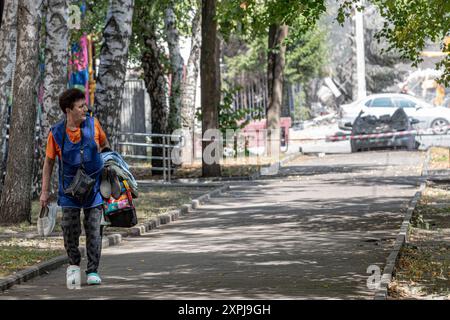 Charkiv, Ukraine. August 2024. Eine Frau, die ein Paar zusätzliche Schuhe und Kleidung in sich hat, zieht sich aus der Nachbarschaft zurück, wo ein russischer Streik ein Gebäude traf. Der Angriff auf Charkiw am Dienstag, den 6. August 2024, führte zu 8 Verletzten und umfangreichen Schäden an 15 Gebäuden, Büros, einer Poliklinik, einer Universität und 25 Autos. (VX Photo/ Vudi Xhymshiti) Credit: VX Pictures/Alamy Live News Credit: VX Pictures/Alamy Live News Stockfoto