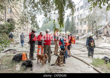 Charkiv, Ukraine. August 2024. Such- und Rettungseinheiten, begleitet von ihren Hundepartnern, stehen bereit, den Tatort zu betreten, um menschliche Überreste in den Trümmern aufzudecken. Der russische Angriff auf Charkiw am Dienstag, den 6. August 2024, führte zu 8 Verletzungen und erheblichen Schäden an 15 Gebäuden, Büros, einer Poliklinik, einer Universität und 25 Autos. (VX Photo/Vudi Xhymshiti). Credit: VX Pictures/Alamy Live News Credit: VX Pictures/Alamy Live News Stockfoto