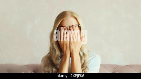 Müde überarbeitete Angestellte, die sich die Augen reibt, unter Augenanstrengung, trockenem Auge-Syndrom Stockfoto