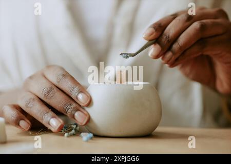 Hold Candle Wick Trimmer mit beigefarbener Kerze im Becher Stockfoto