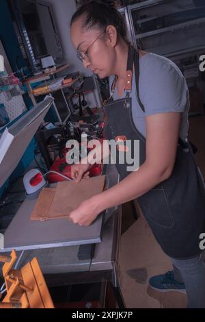 Die junge arbeitende Frau in ihrer Werkstatt macht den Sublimationsprozess mit einem Etikettenschild-, Druck- und Grafikdesign-Konzept. Stockfoto