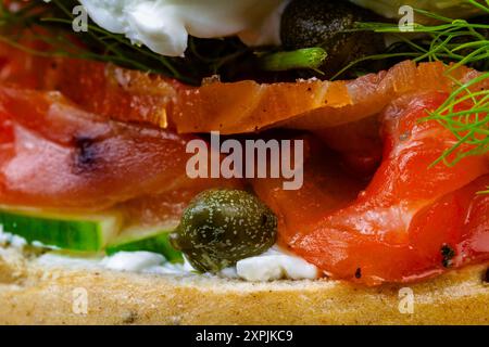 Makro aus hausgemachtem und geräuchertem Lachsbagel, mit Frischkäse, Kapern, Gurke und Dill. Stockfoto