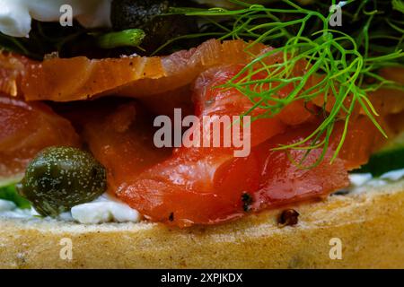 Makro aus hausgemachtem und geräuchertem Lachsbagel, mit Frischkäse, Kapern, Gurke und Dill, Landschaft. Stockfoto