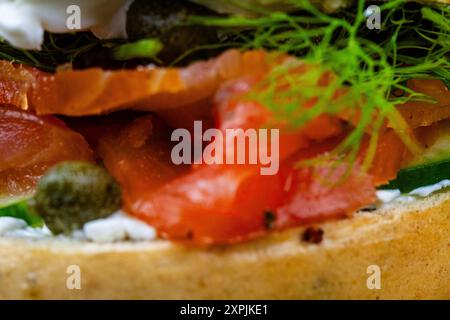 Unscharfe oder defokussierte Makros von hausgemachtem und geräuchertem Lachsbagel, mit Frischkäse, Kapern, Gurke und Dill, Landschaft, Hintergrund. Stockfoto