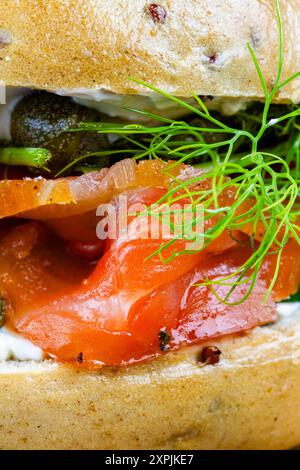 Makro aus hausgemachtem und geräuchertem Lachsbagel, mit Frischkäse, Kapern, Gurke und Dill, Porträt. Stockfoto