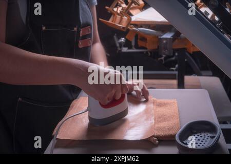 Die junge arbeitende Frau in ihrer Werkstatt macht den Sublimationsprozess mit einem Etikettenschild-, Druck- und Grafikdesign-Konzept. Stockfoto