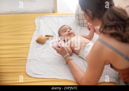 Mutter und Tochter spielen beim Windelwechsel die Hand. Mutterschaft. Stockfoto