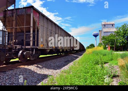 Hinckley, Illinois, USA. Ein leerer Kohlezug der Burlington Northern Santa Fe Railway verwischt leicht von seiner Bewegung, während er an einem alten Getreideelevator vorbeifährt. Stockfoto