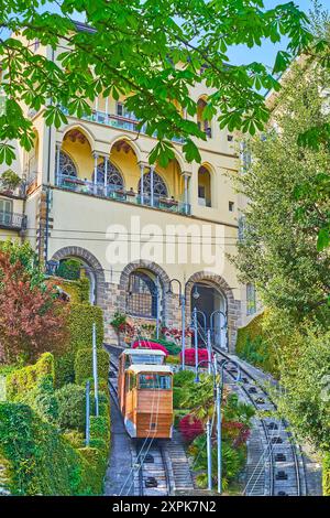 Der steile Hang mit einem Oldtimer der Seilbahn Citta Alta (Oberstadt) (Funicolare Bergamo Alta) mit üppig grünen Rosskastanienbäumen in der Stockfoto