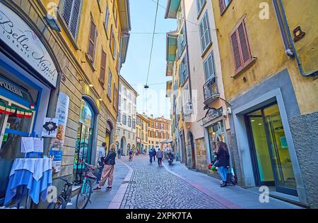 BERGAMO, ITALIEN - 7. APRIL 2022: Die enge kurvenreiche Touristenstraße Sant'Alessandro mit Cafés, Restaurants und Geschäften, Bergamo, Italien Stockfoto