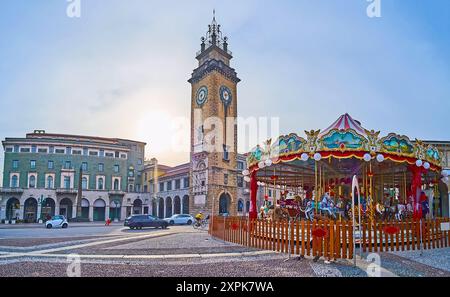 Das Karussell im Vintage-Stil gegen die Viale Roma und den Gedenkturm (Torre dei Caduti) auf der Piazza Vittorio Veneto, Citta Bassa, Bergamo, Italien Stockfoto