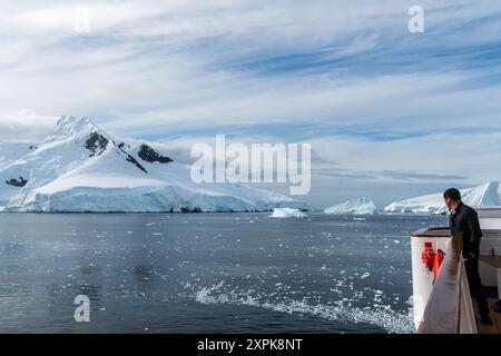 Graham Passage, Antarktische Halbinsel - 1. Februar 2024. Ein Besatzungsmitglied blickt über die Eisberge und Gletscherlandschaft der antarktischen Halbinsel in der Nähe der Graham Passage. Stockfoto